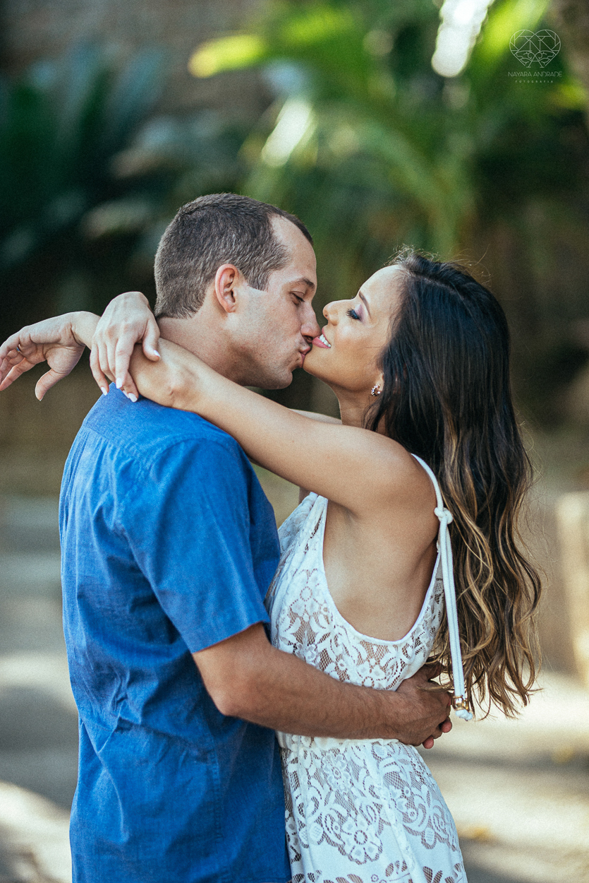 fotografia pre wedding de casal na praia noiva de vestido branco casal fazendo fotos em poses inspiração pela fotografa nayara andrade lindo por do sol colorido e fotos artisticas pela fotografa premiada mundialmente casamentos de dia inspiração