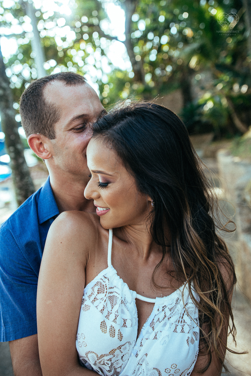 fotografia pre wedding de casal na praia noiva de vestido branco casal fazendo fotos em poses inspiração pela fotografa nayara andrade lindo por do sol colorido e fotos artisticas pela fotografa premiada mundialmente casamentos de dia inspiração