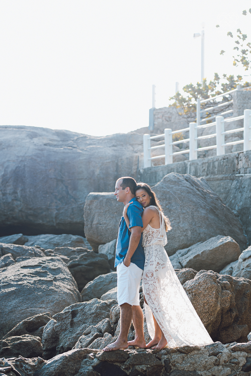 fotografia pre wedding de casal na praia noiva de vestido branco casal fazendo fotos em poses inspiração pela fotografa nayara andrade lindo por do sol colorido e fotos artisticas pela fotografa premiada mundialmente casamentos de dia inspiração