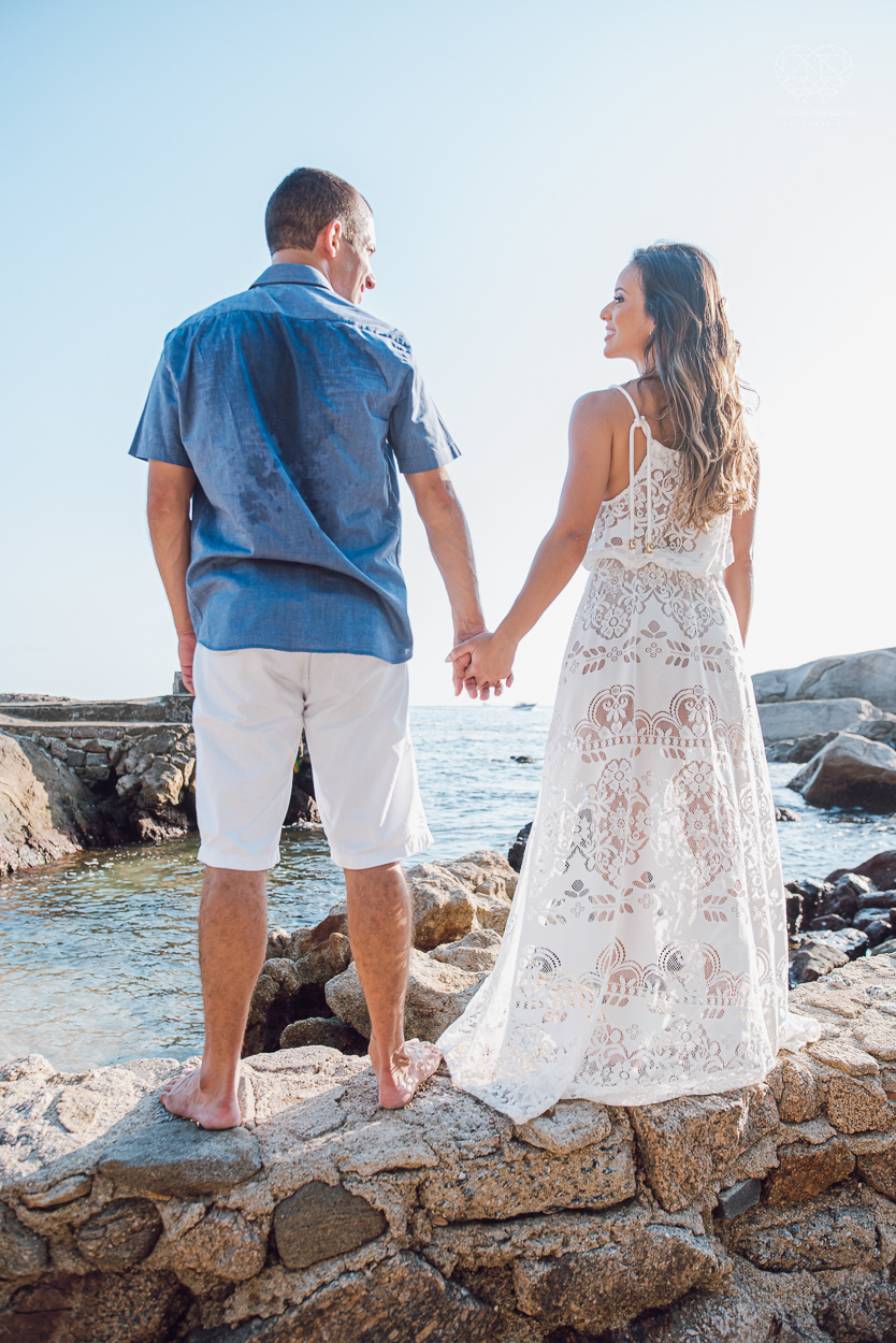 fotografia pre wedding de casal na praia noiva de vestido branco casal fazendo fotos em poses inspiração pela fotografa nayara andrade lindo por do sol colorido e fotos artisticas pela fotografa premiada mundialmente casamentos de dia inspiração
