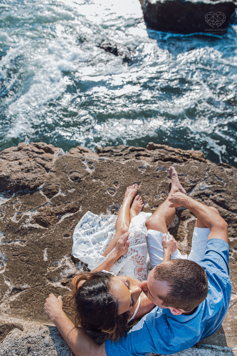 fotografia pre wedding de casal na praia noiva de vestido branco casal fazendo fotos em poses inspiração pela fotografa nayara andrade lindo por do sol colorido e fotos artisticas pela fotografa premiada mundialmente casamentos de dia inspiração