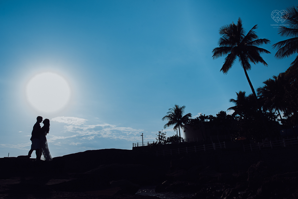 fotografia pre wedding de casal na praia noiva de vestido branco casal fazendo fotos em poses inspiração pela fotografa nayara andrade lindo por do sol colorido e fotos artisticas pela fotografa premiada mundialmente casamentos de dia inspiração
