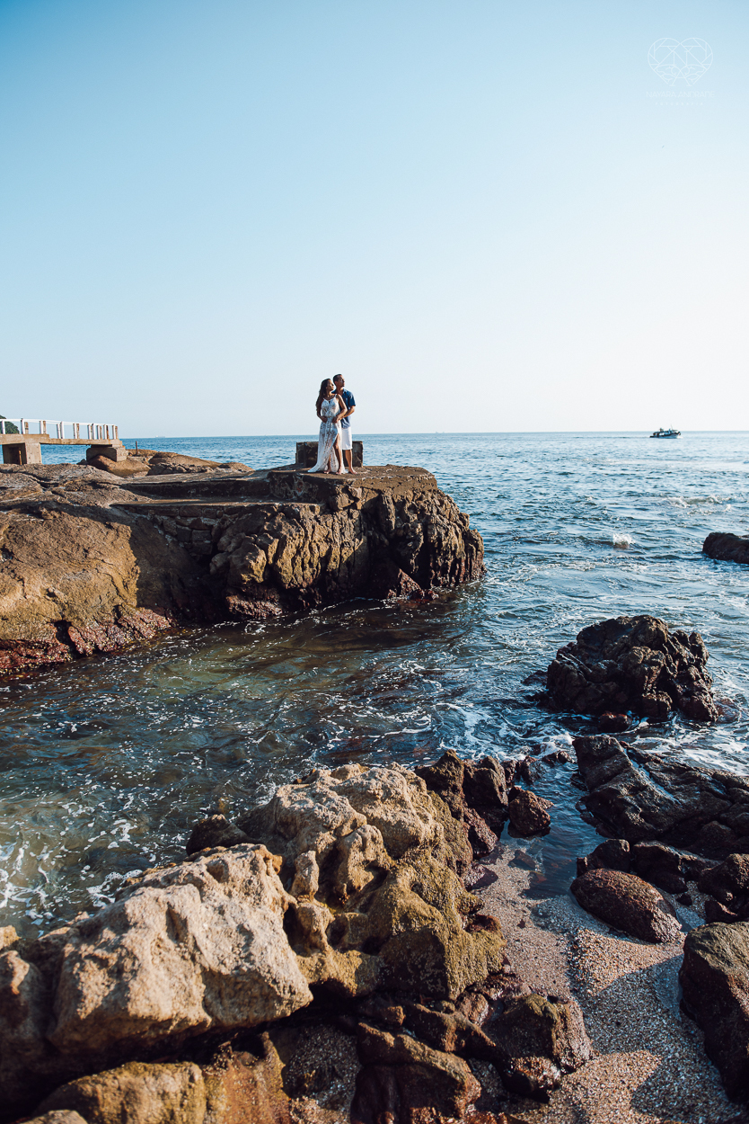 fotografia pre wedding de casal na praia noiva de vestido branco casal fazendo fotos em poses inspiração pela fotografa nayara andrade lindo por do sol colorido e fotos artisticas pela fotografa premiada mundialmente casamentos de dia inspiração