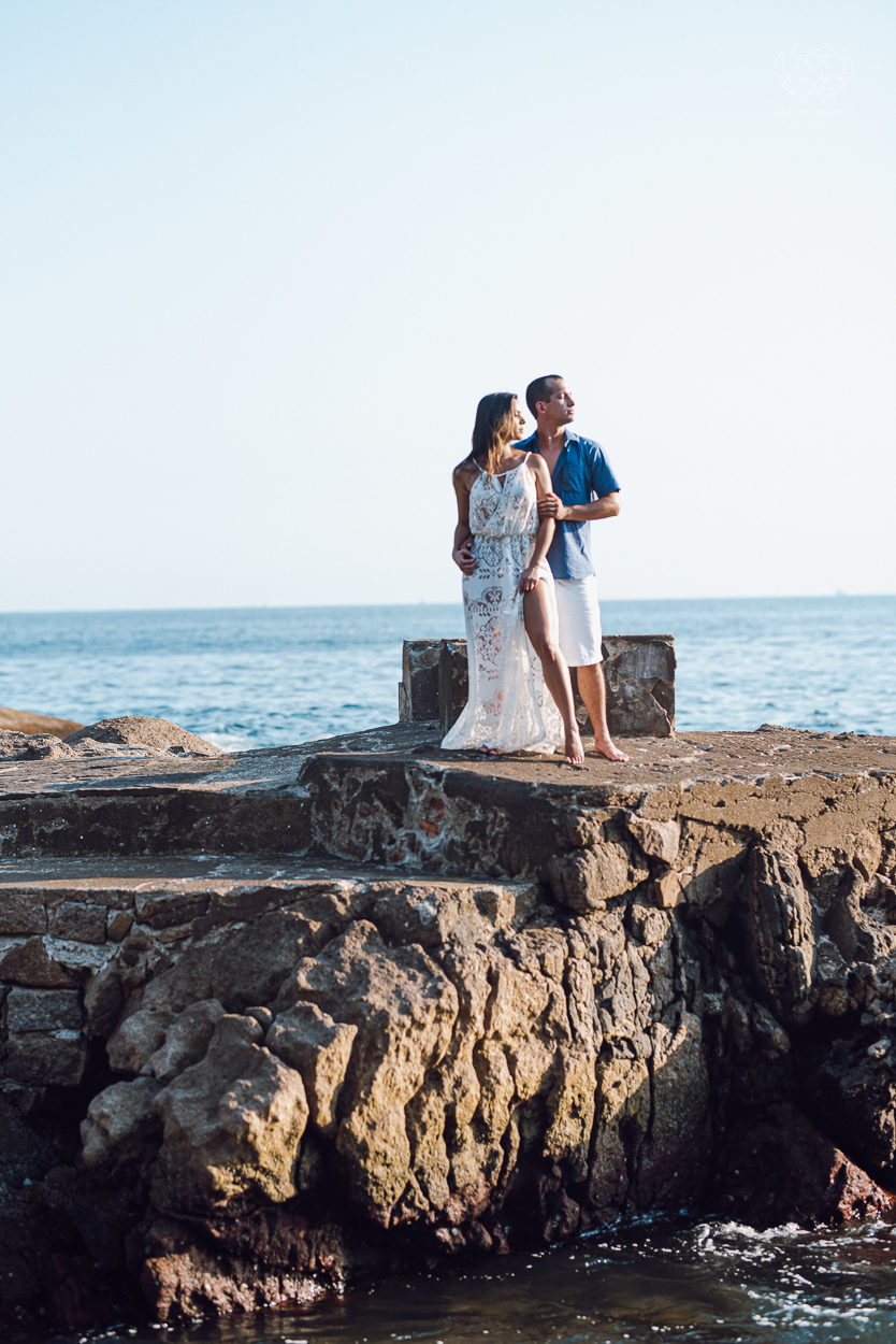 fotografia pre wedding de casal na praia noiva de vestido branco casal fazendo fotos em poses inspiração pela fotografa nayara andrade lindo por do sol colorido e fotos artisticas pela fotografa premiada mundialmente casamentos de dia inspiração