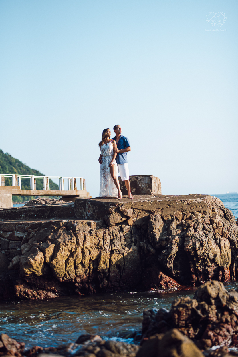 fotografia pre wedding de casal na praia noiva de vestido branco casal fazendo fotos em poses inspiração pela fotografa nayara andrade lindo por do sol colorido e fotos artisticas pela fotografa premiada mundialmente casamentos de dia inspiração