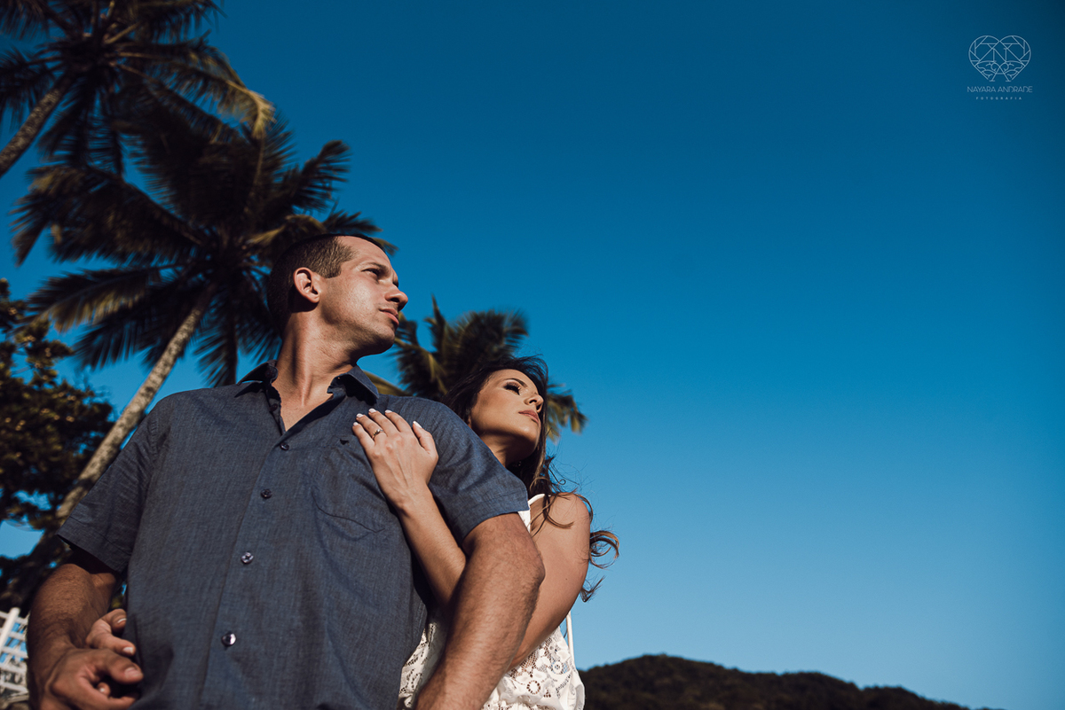 fotografia pre wedding de casal na praia noiva de vestido branco casal fazendo fotos em poses inspiração pela fotografa nayara andrade lindo por do sol colorido e fotos artisticas pela fotografa premiada mundialmente casamentos de dia inspiração