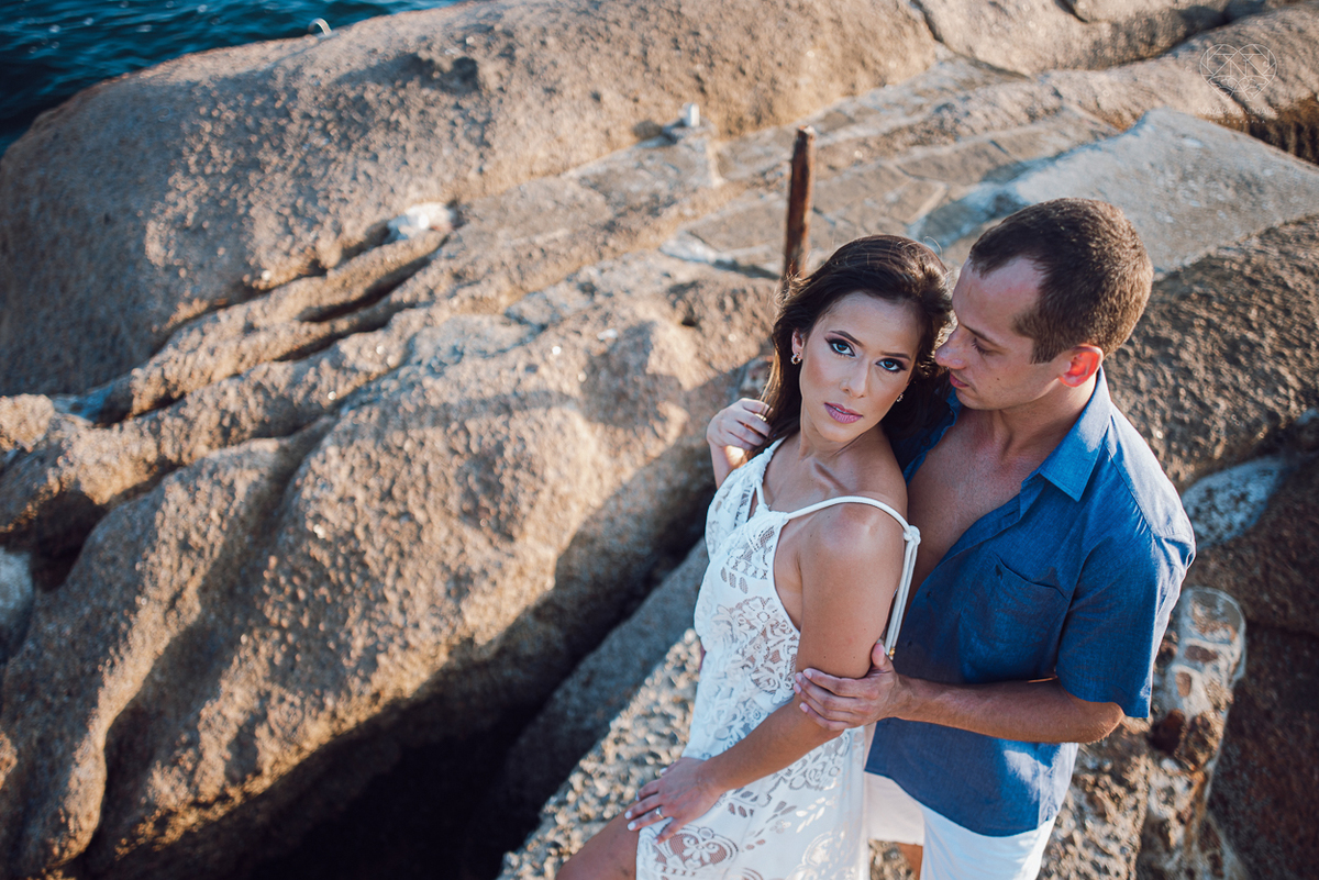 fotografia pre wedding de casal na praia noiva de vestido branco casal fazendo fotos em poses inspiração pela fotografa nayara andrade lindo por do sol colorido e fotos artisticas pela fotografa premiada mundialmente casamentos de dia inspiração