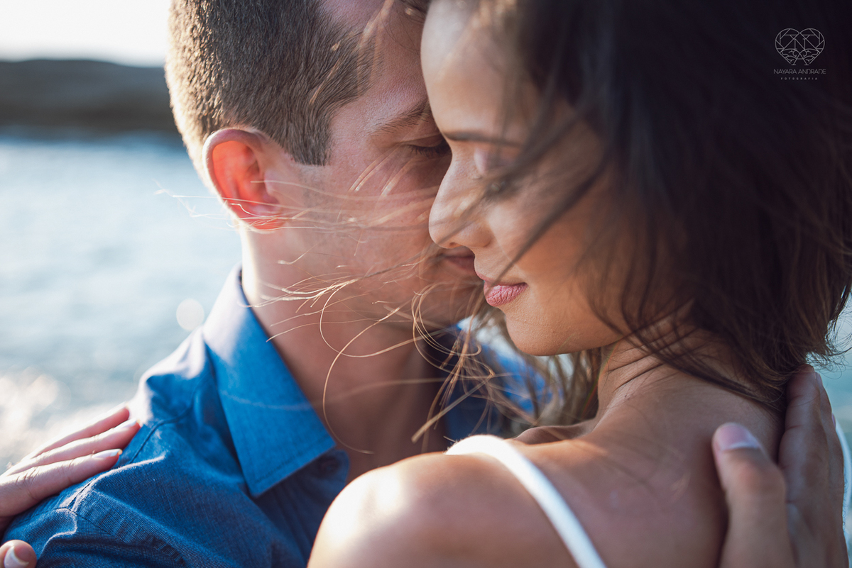 fotografia pre wedding de casal na praia noiva de vestido branco casal fazendo fotos em poses inspiração pela fotografa nayara andrade lindo por do sol colorido e fotos artisticas pela fotografa premiada mundialmente casamentos de dia inspiração