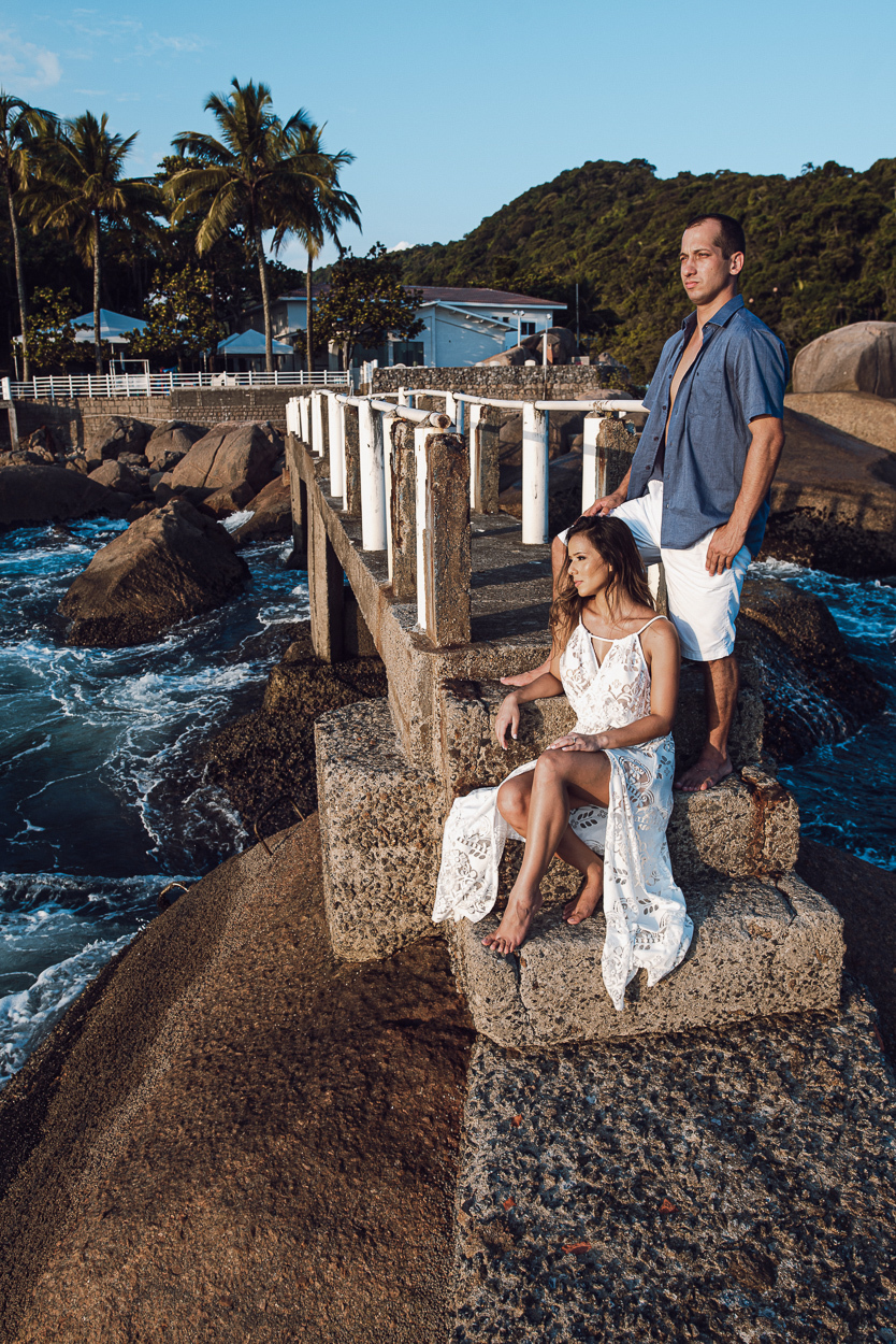 fotografia pre wedding de casal na praia noiva de vestido branco casal fazendo fotos em poses inspiração pela fotografa nayara andrade lindo por do sol colorido e fotos artisticas pela fotografa premiada mundialmente casamentos de dia inspiração