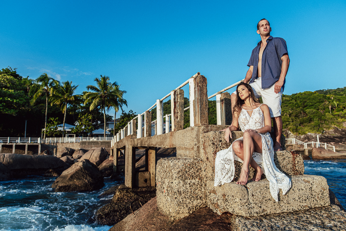fotografia pre wedding de casal na praia noiva de vestido branco casal fazendo fotos em poses inspiração pela fotografa nayara andrade lindo por do sol colorido e fotos artisticas pela fotografa premiada mundialmente casamentos de dia inspiração