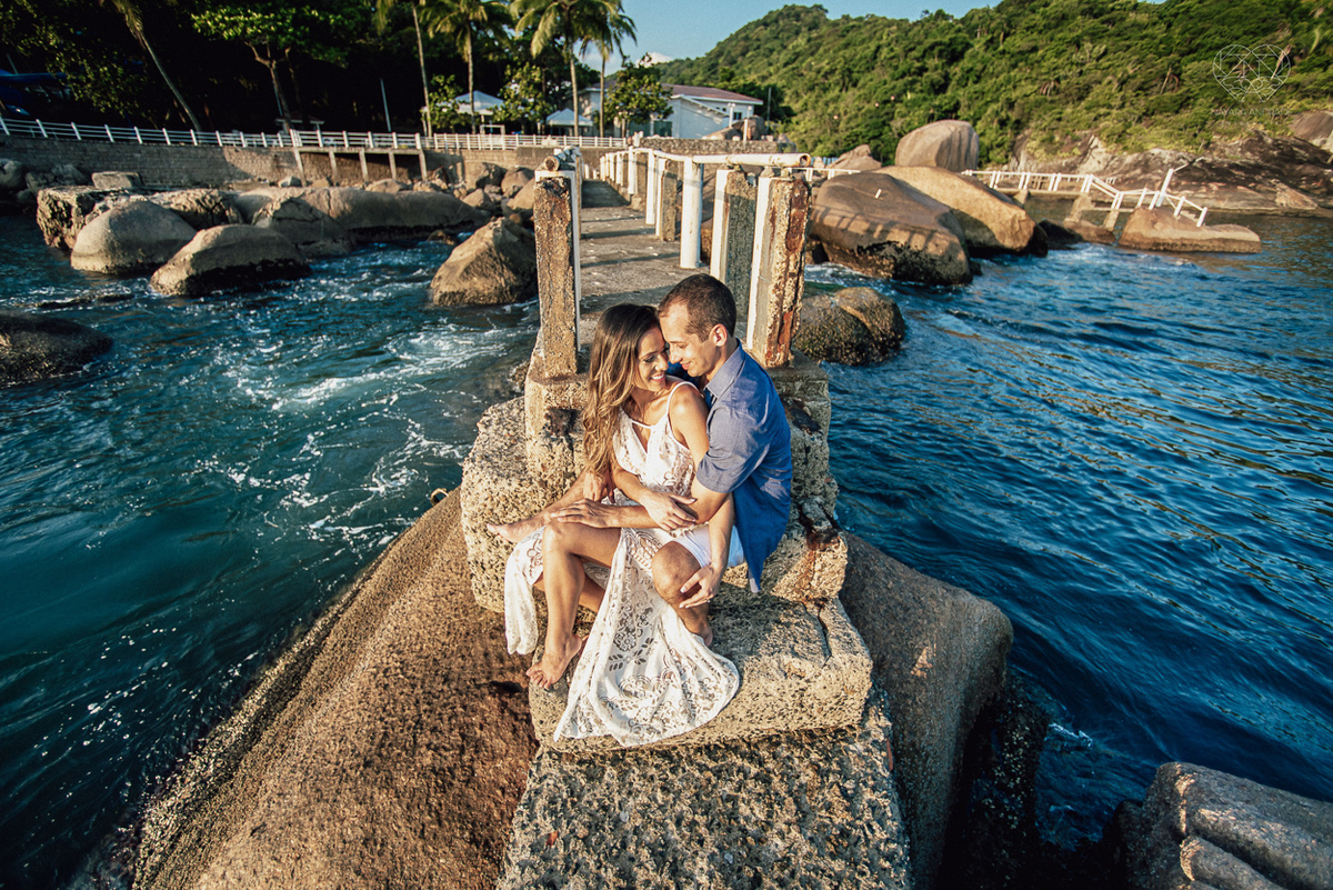 fotografia pre wedding de casal na praia noiva de vestido branco casal fazendo fotos em poses inspiração pela fotografa nayara andrade lindo por do sol colorido e fotos artisticas pela fotografa premiada mundialmente casamentos de dia inspiração