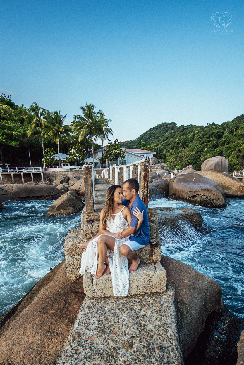 fotografia pre wedding de casal na praia noiva de vestido branco casal fazendo fotos em poses inspiração pela fotografa nayara andrade lindo por do sol colorido e fotos artisticas pela fotografa premiada mundialmente casamentos de dia inspiração