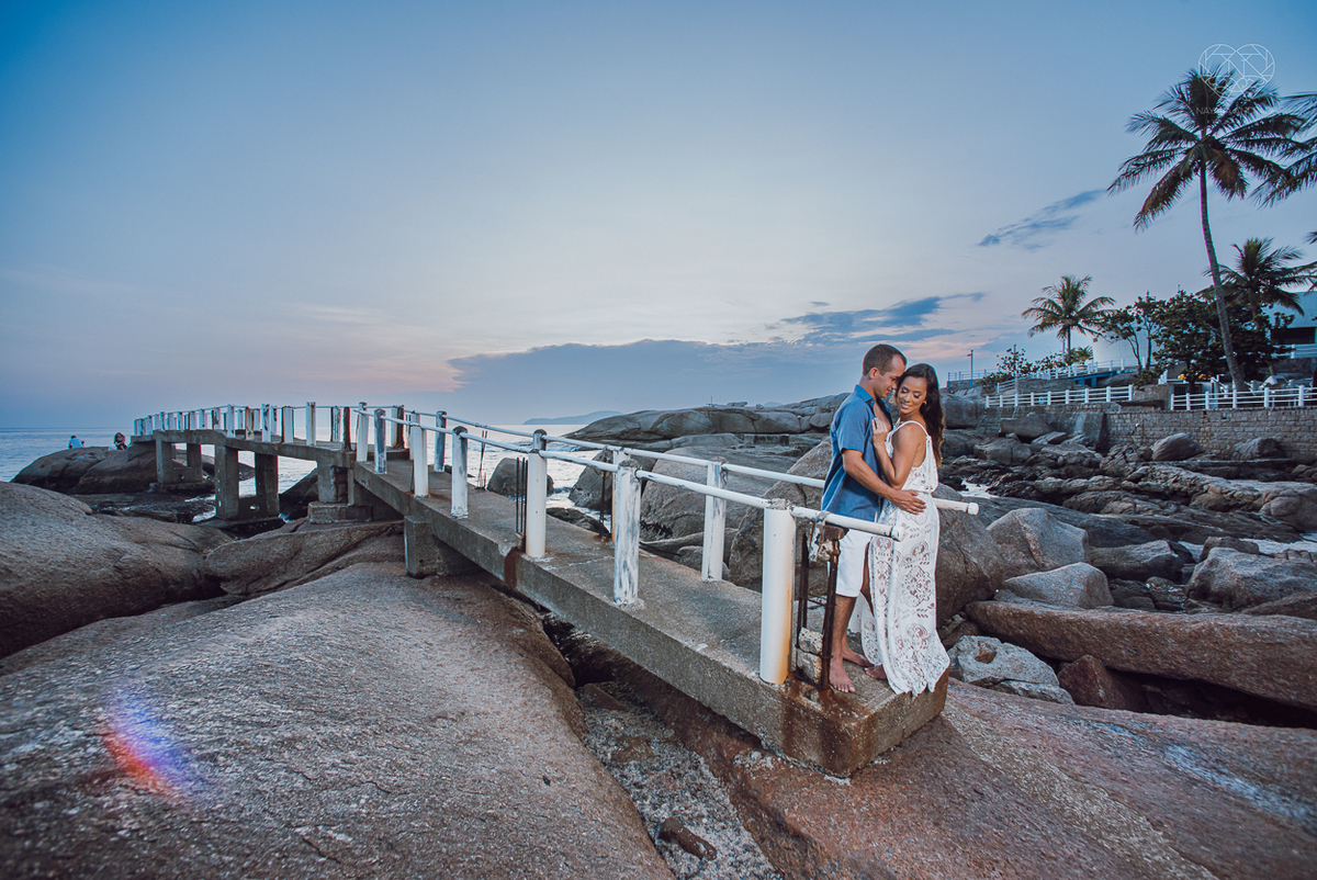 fotografia pre wedding de casal na praia noiva de vestido branco casal fazendo fotos em poses inspiração pela fotografa nayara andrade lindo por do sol colorido e fotos artisticas pela fotografa premiada mundialmente casamentos de dia inspiração