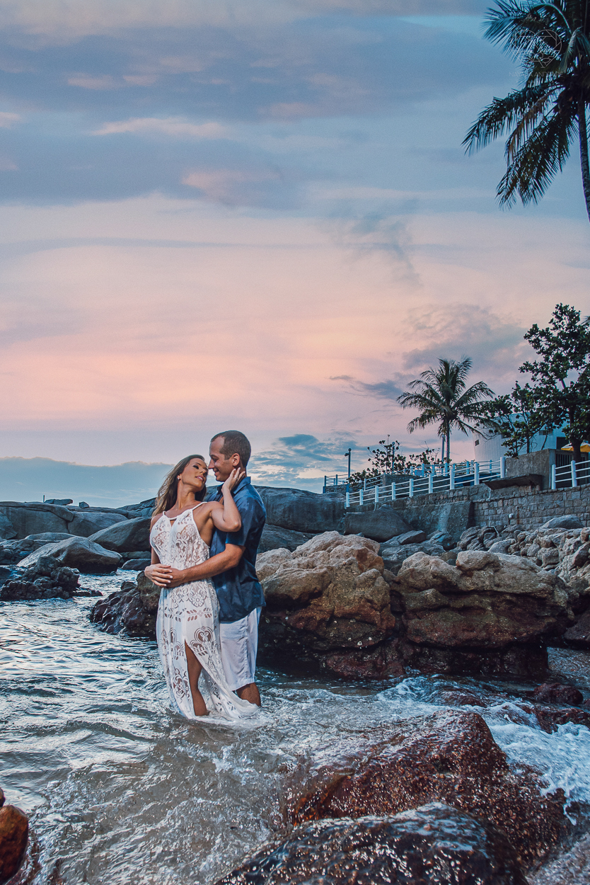 fotografia pre wedding de casal na praia noiva de vestido branco casal fazendo fotos em poses inspiração pela fotografa nayara andrade lindo por do sol colorido e fotos artisticas pela fotografa premiada mundialmente casamentos de dia inspiração