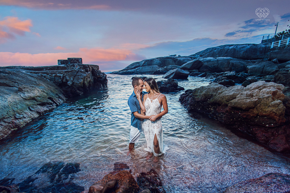 fotografia pre wedding de casal na praia noiva de vestido branco casal fazendo fotos em poses inspiração pela fotografa nayara andrade lindo por do sol colorido e fotos artisticas pela fotografa premiada mundialmente casamentos de dia inspiração