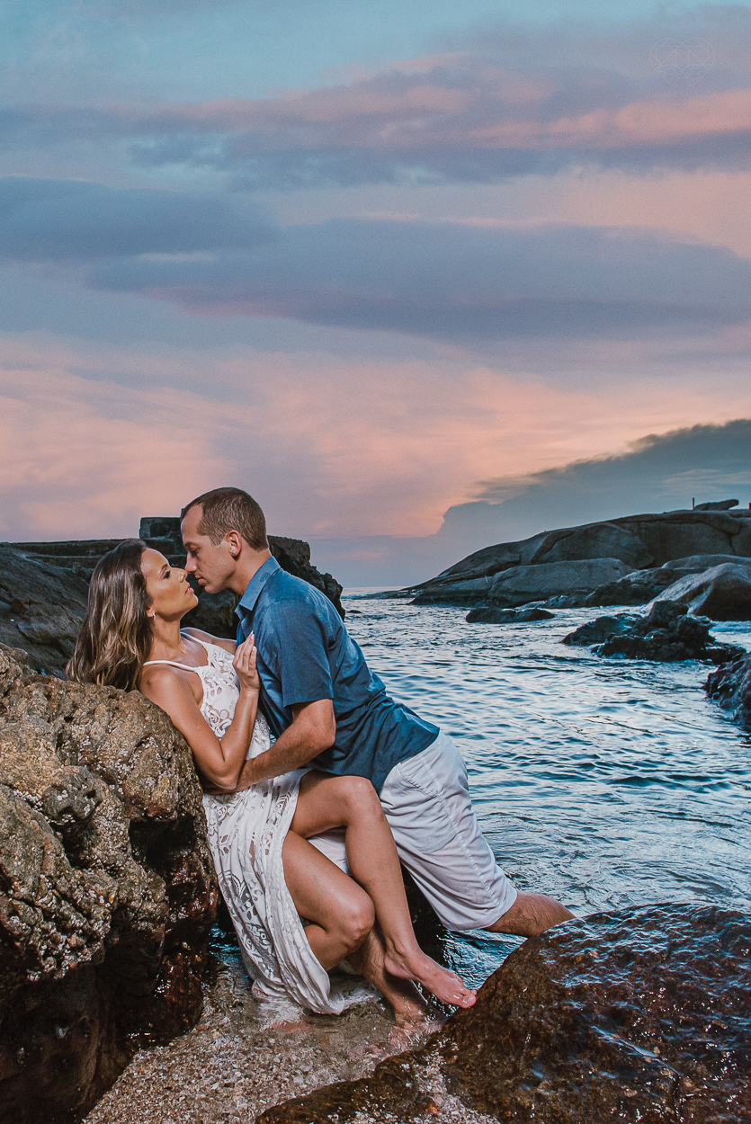 fotografia pre wedding de casal na praia noiva de vestido branco casal fazendo fotos em poses inspiração pela fotografa nayara andrade lindo por do sol colorido e fotos artisticas pela fotografa premiada mundialmente casamentos de dia inspiração