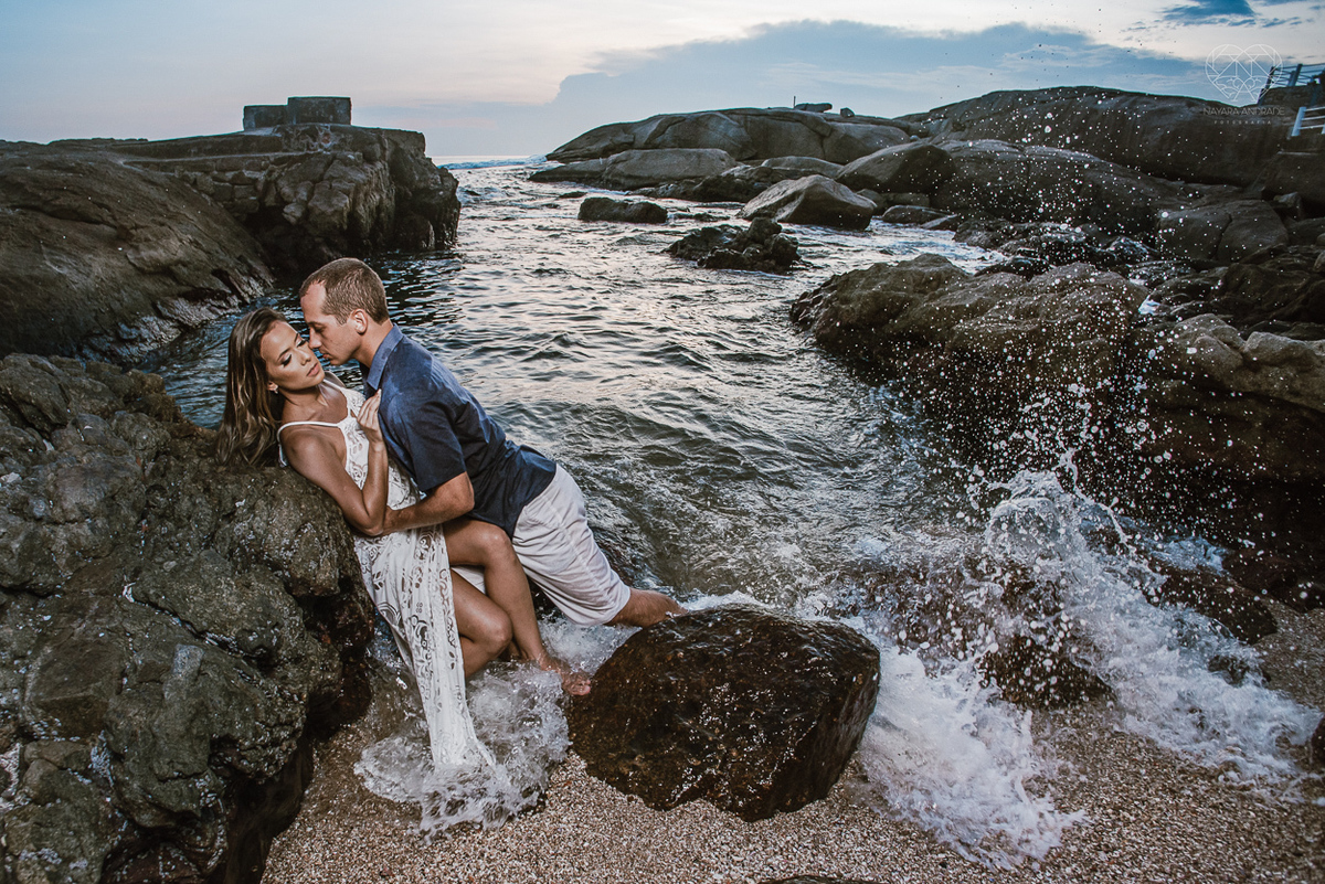 fotografia pre wedding de casal na praia noiva de vestido branco casal fazendo fotos em poses inspiração pela fotografa nayara andrade lindo por do sol colorido e fotos artisticas pela fotografa premiada mundialmente casamentos de dia inspiração