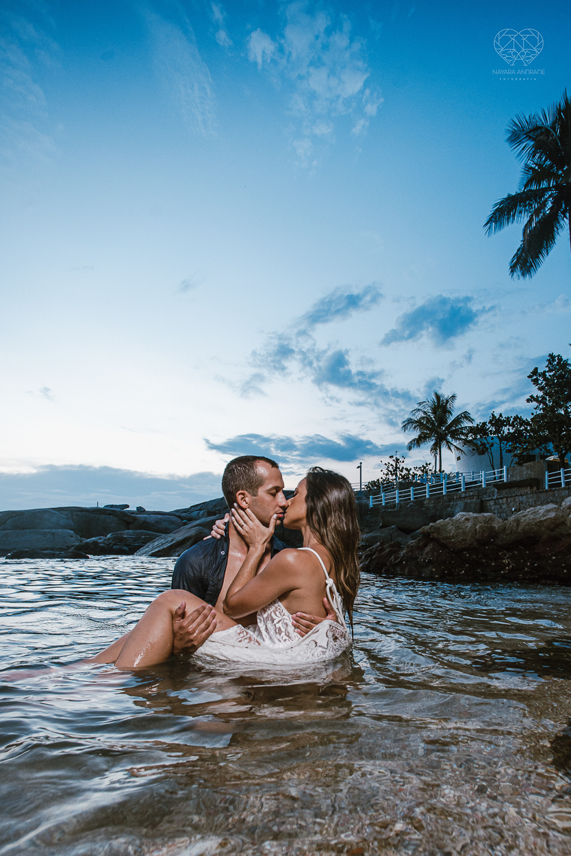 fotografia pre wedding de casal na praia noiva de vestido branco casal fazendo fotos em poses inspiração pela fotografa nayara andrade lindo por do sol colorido e fotos artisticas pela fotografa premiada mundialmente casamentos de dia inspiração