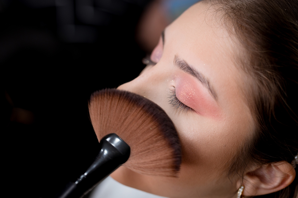 Noiva sendo maquiada pela maquiadora Taiane Lima, espalhando o blush pelo rosto