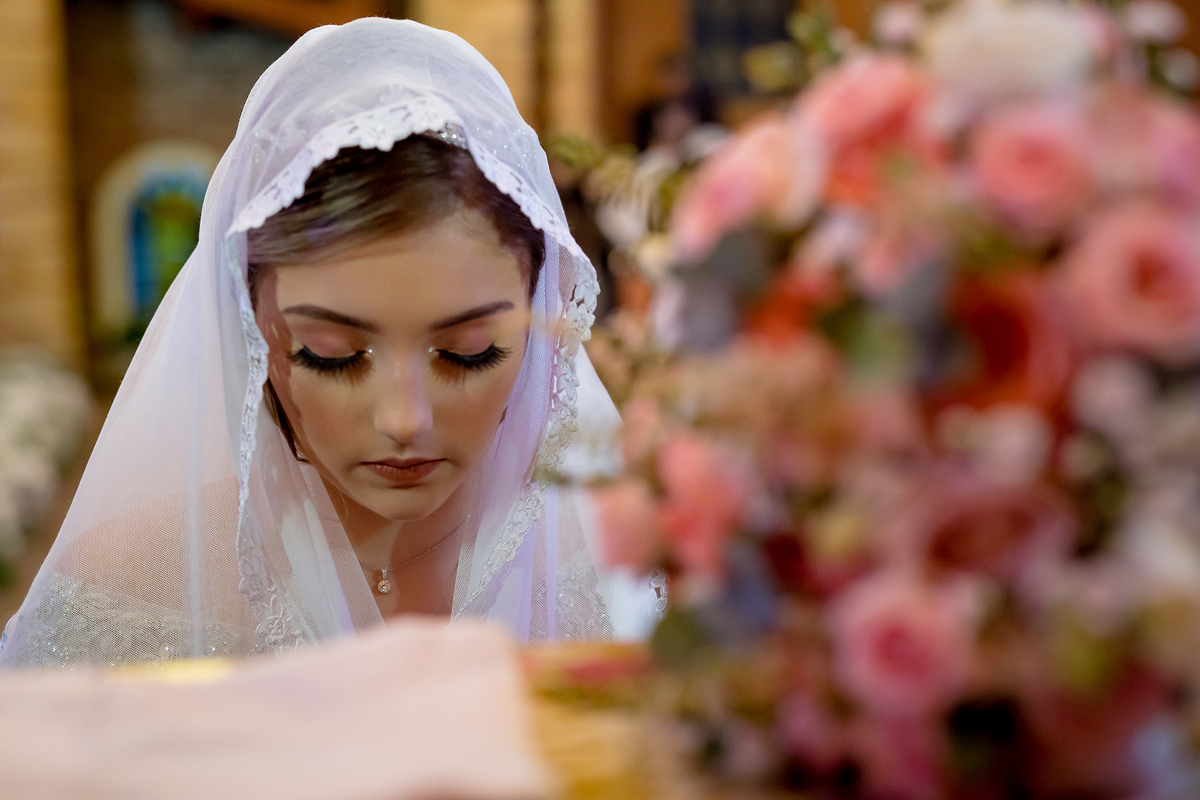 Noiva com a sua mantilha da congregação por cima de sua cabeça para o momento de oração