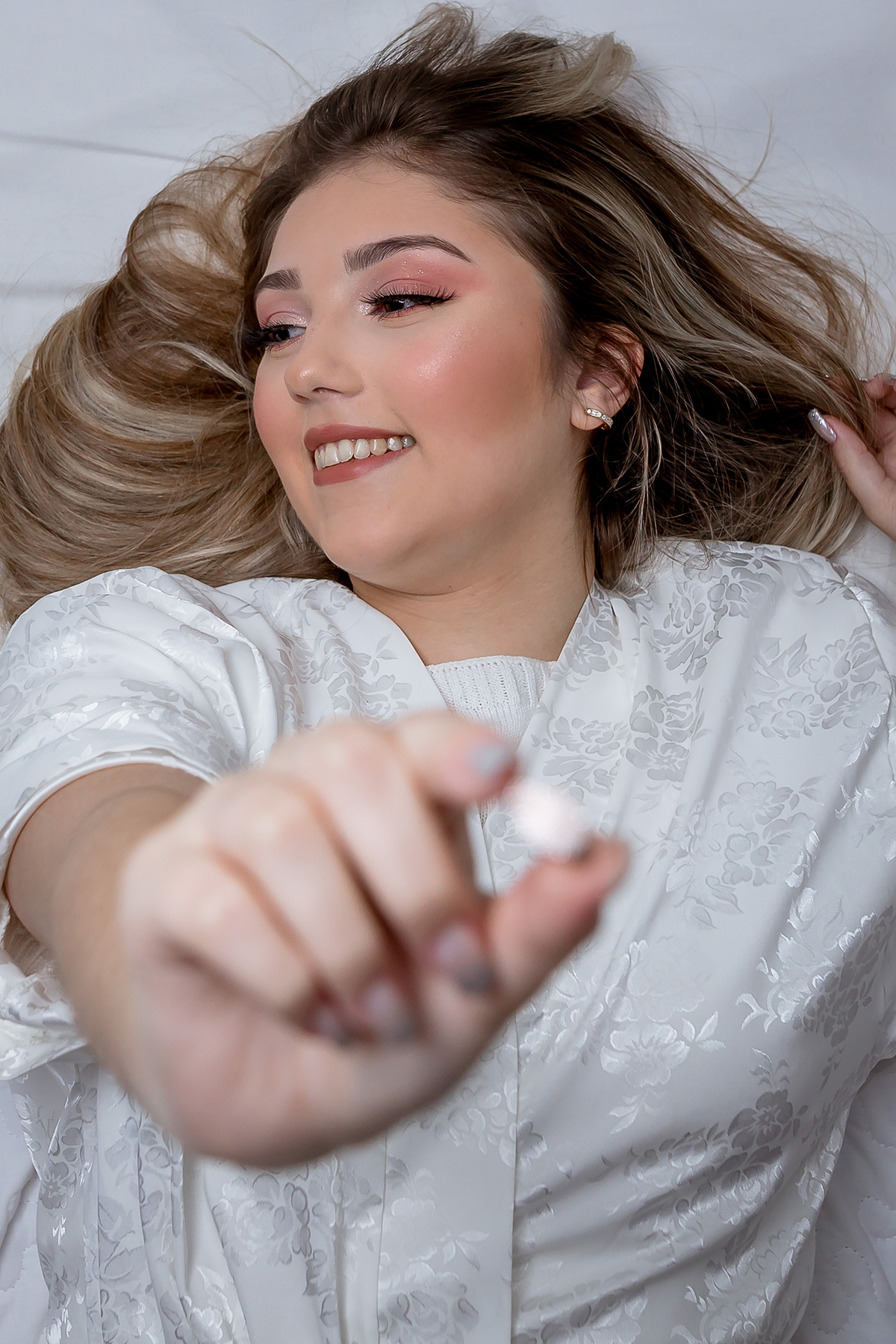 Detalhes da noiva deitada na cama exibindo sua jóia 