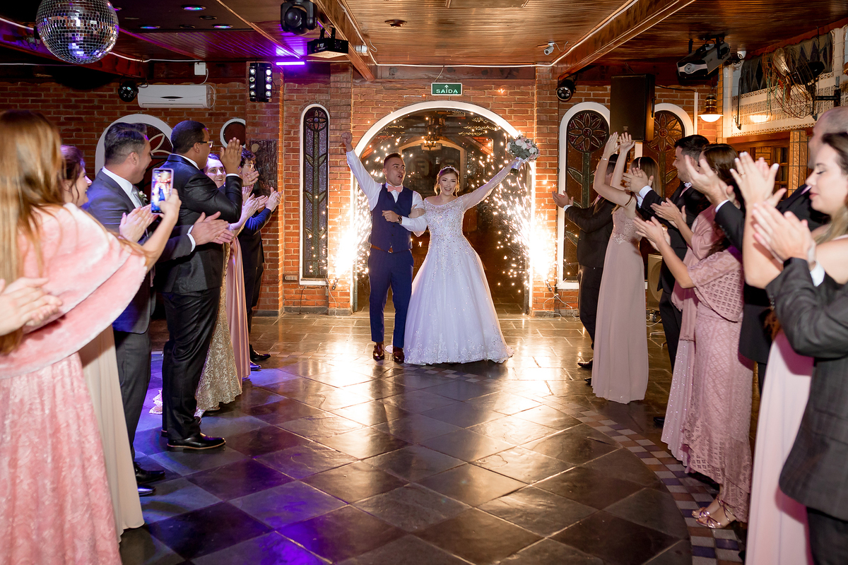 Entrada dos noivos no salão da recepção com todos os padrinhos e madrinhas batendo palmas