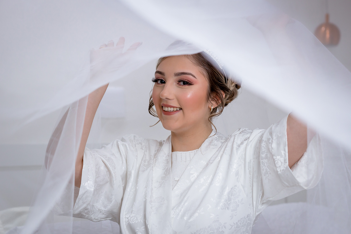 Noiva com o véu por cima da cabeça sorrindo