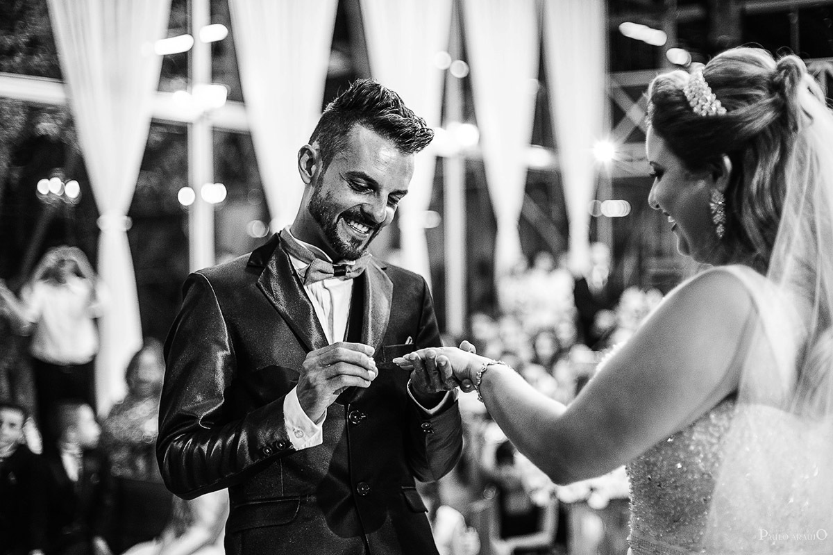 colocando a aliança de casamento nas mãos da noiva.