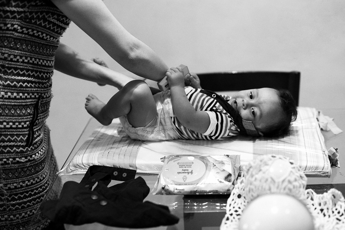 Momentos na vida de pais e filhos, trocando o bebê durante um ensaio de família, foto em P&B. Paulo Araujo