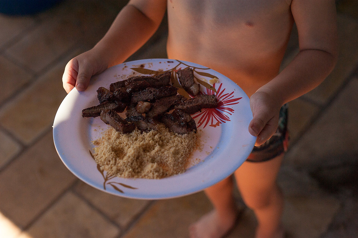 foto Ilha do Porchat - santos - praia de são vicente - fotografia Paulo Araujo, ensaio de família, lifestyle, churrasco na praia, criança almoçando.