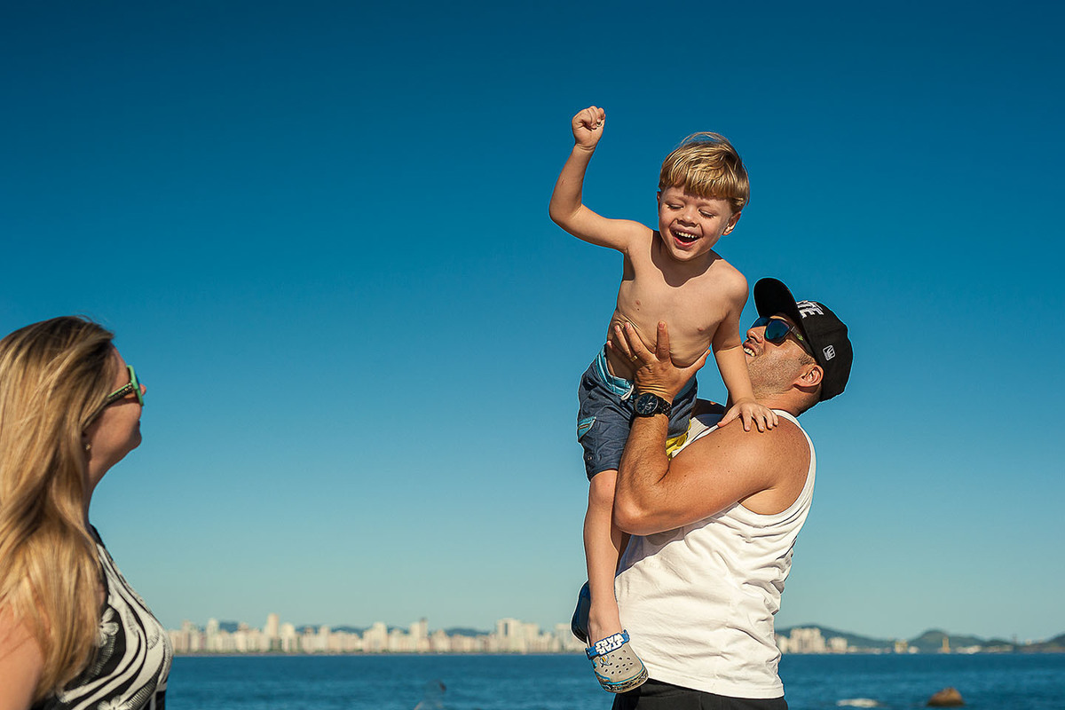 foto Ilha do Porchat - santos - praia de são vicente - fotografia Paulo Araujo, ensaio de família, lifestyle, pai co criança no colo brincando de avião.