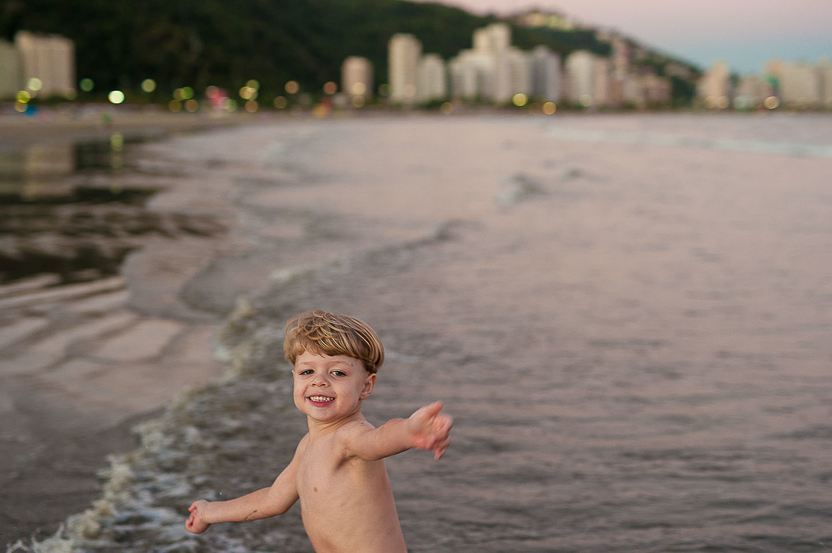 foto Ilha do Porchat - santos - praia de são vicente - fotografia Paulo Araujo, ensaio de família, lifestyle, menino correndo na praia, montanhas e prédios.