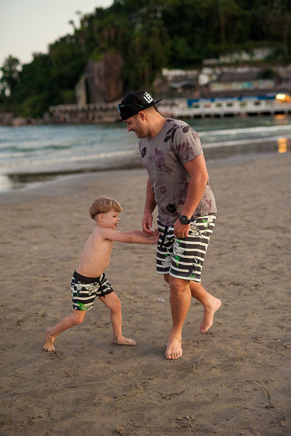 foto Ilha do Porchat - santos - praia de são vicente - fotografia Paulo Araujo, ensaio de família, lifestyle, menino braincando com o pai de luta na areia da praia, pai e filho.
