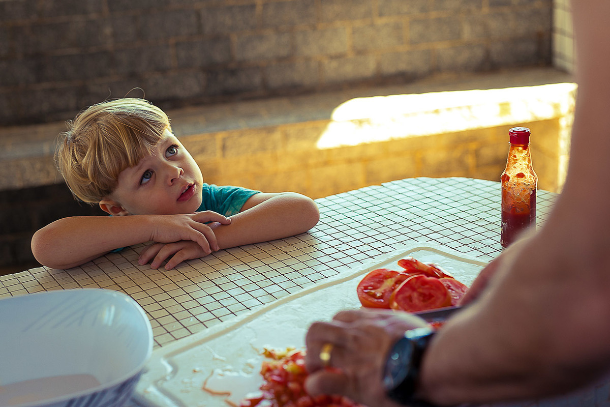 foto Ilha do Porchat - santos - praia de são vicente - fotografia Paulo Araujo, ensaio de família, lifestyle, cortando o tomate para fazer a salada e filho olhando seu pai.