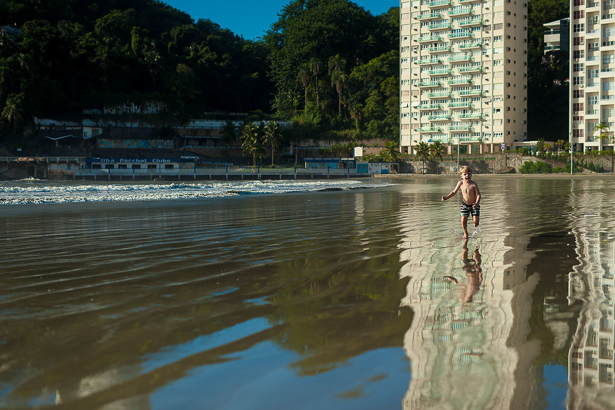 foto Ilha do Porchat - santos - praia de são vicente - fotografia Paulo Araujo, ensaio de família, lifestyle, corrrendo na praia com prédios no fundo, e espelho de água.