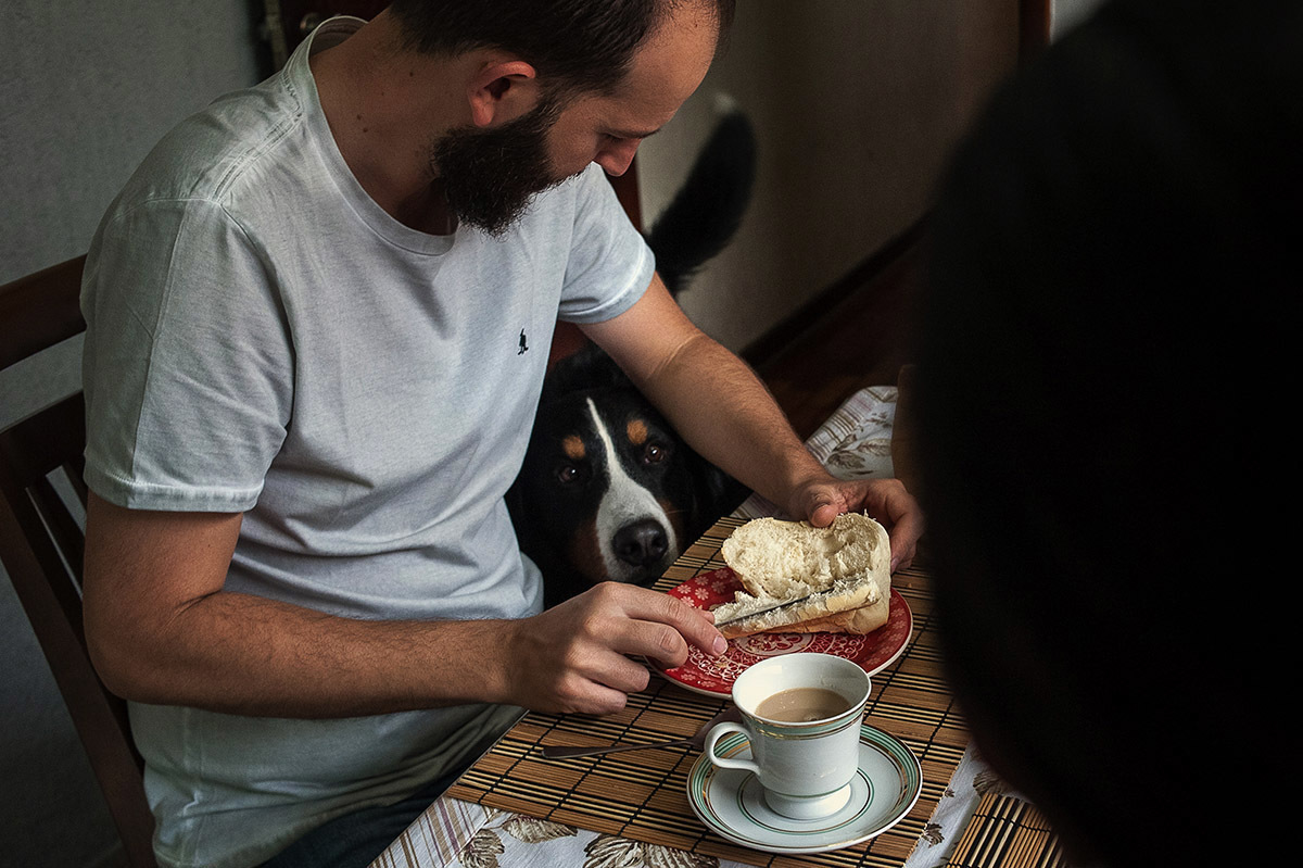 cachorro esperando o dono dar um pedaço de pão, com os olhar de piedade, fotografia de família.