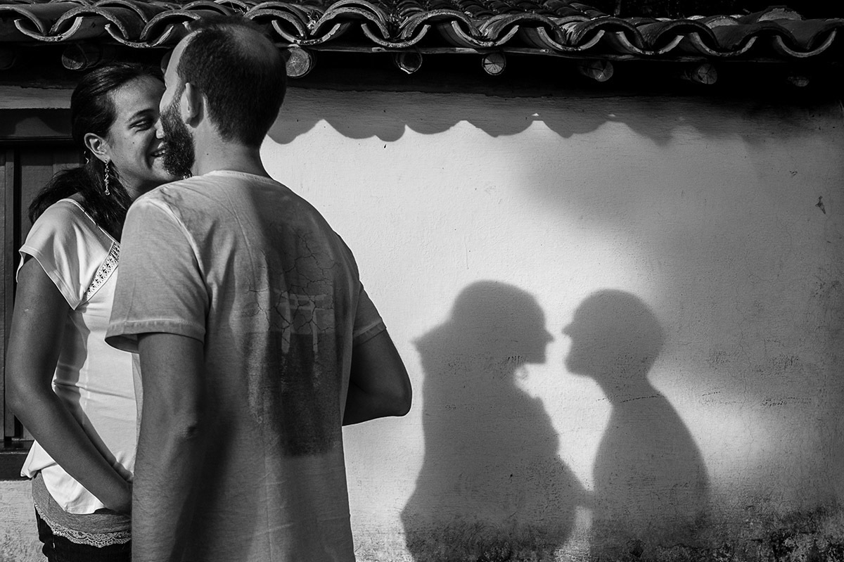 Foto criativa de casal em ensaio fotográfico de gestante, sombra do casal projetada na parede.