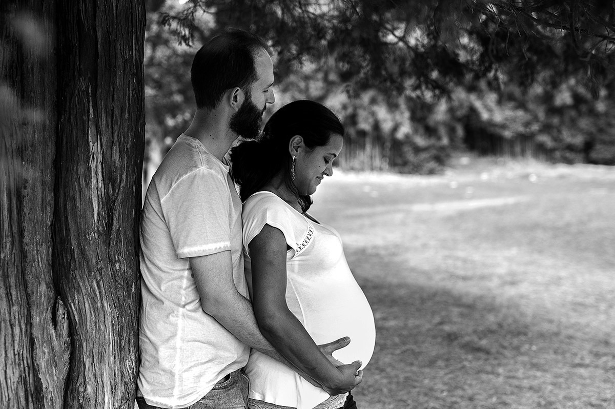 Casal namorando em ensaio de gestante, mão na bariga, carinho.
