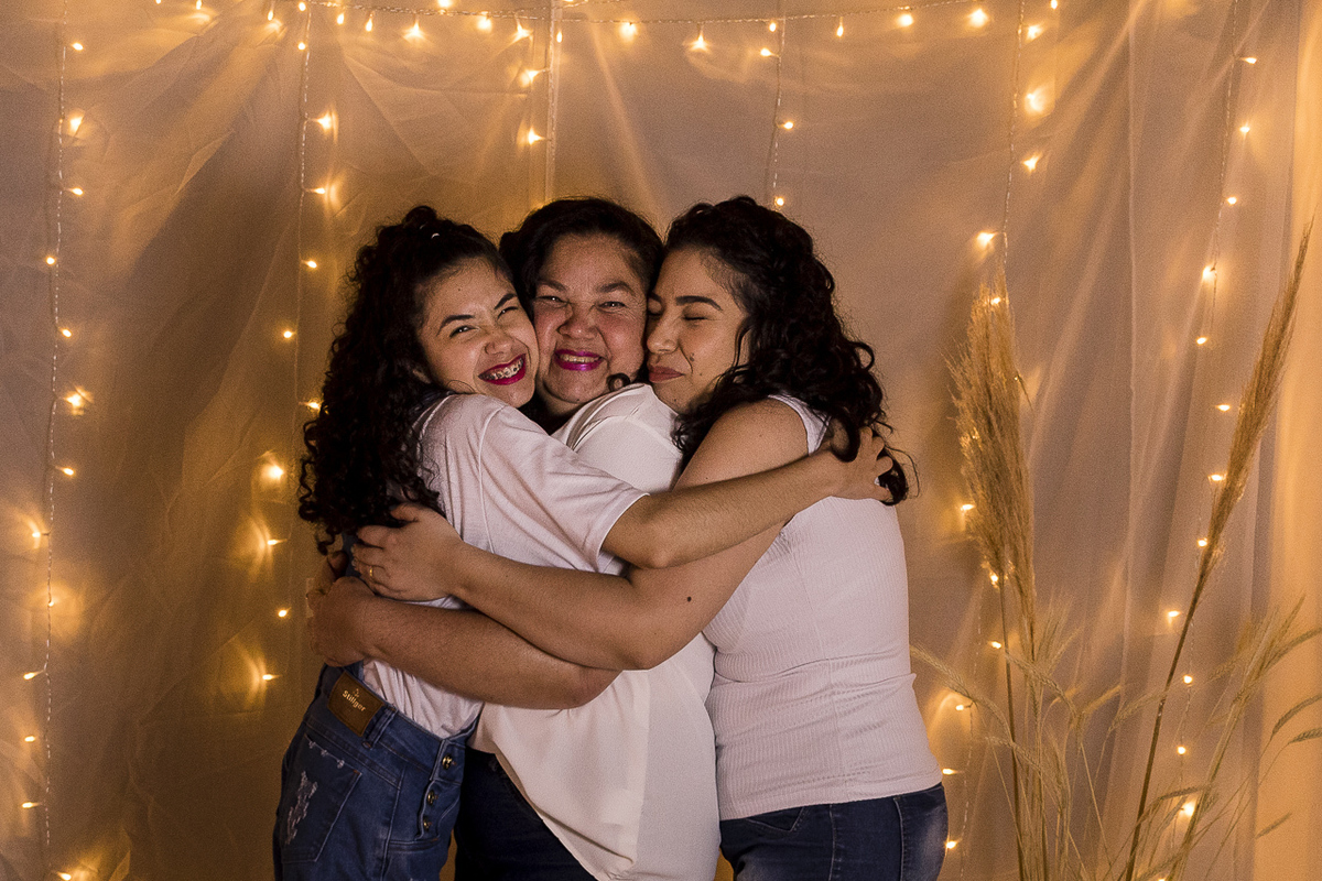 Foto de mãe e filhas se abraçando