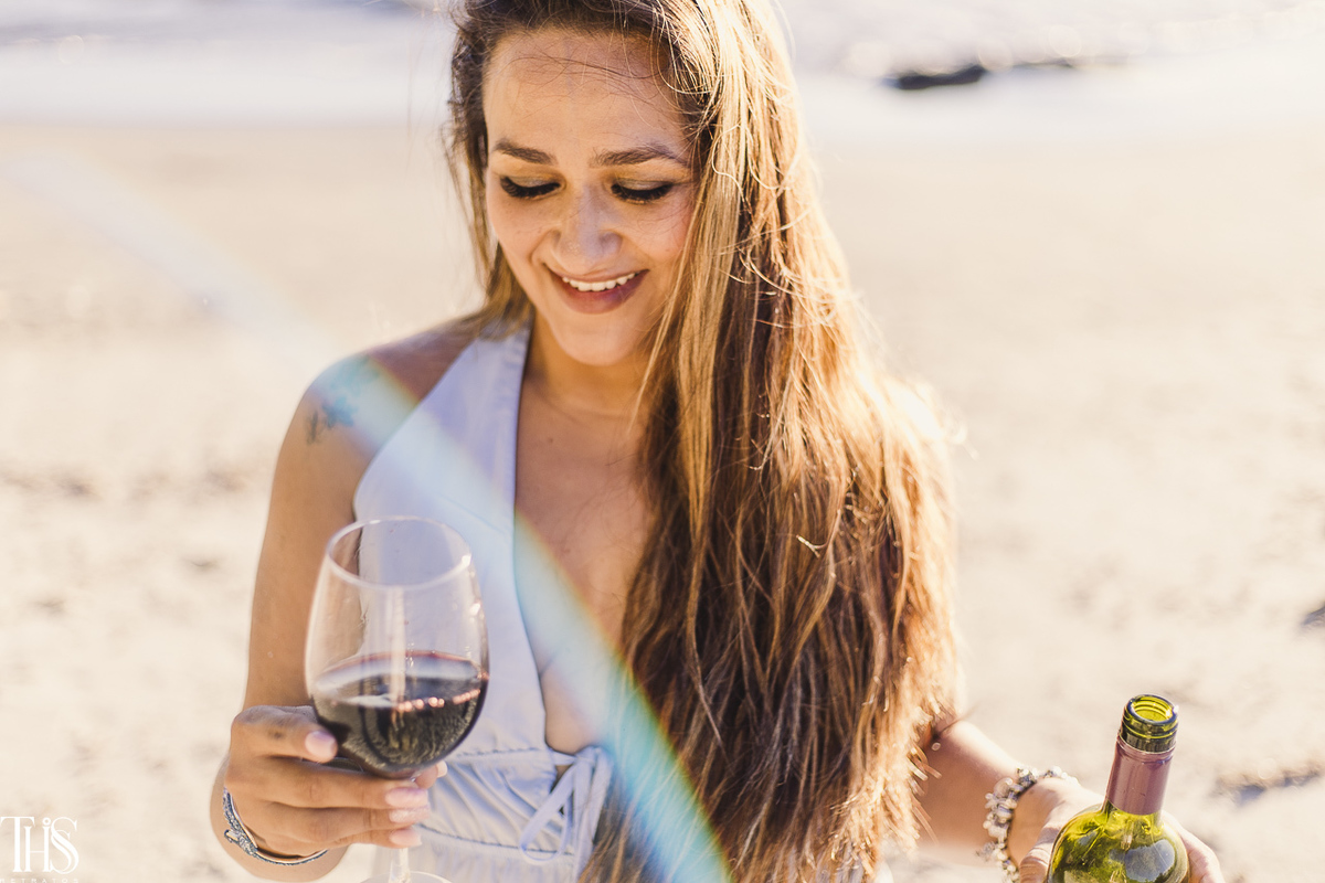 Mulher bebendo vinho na praia