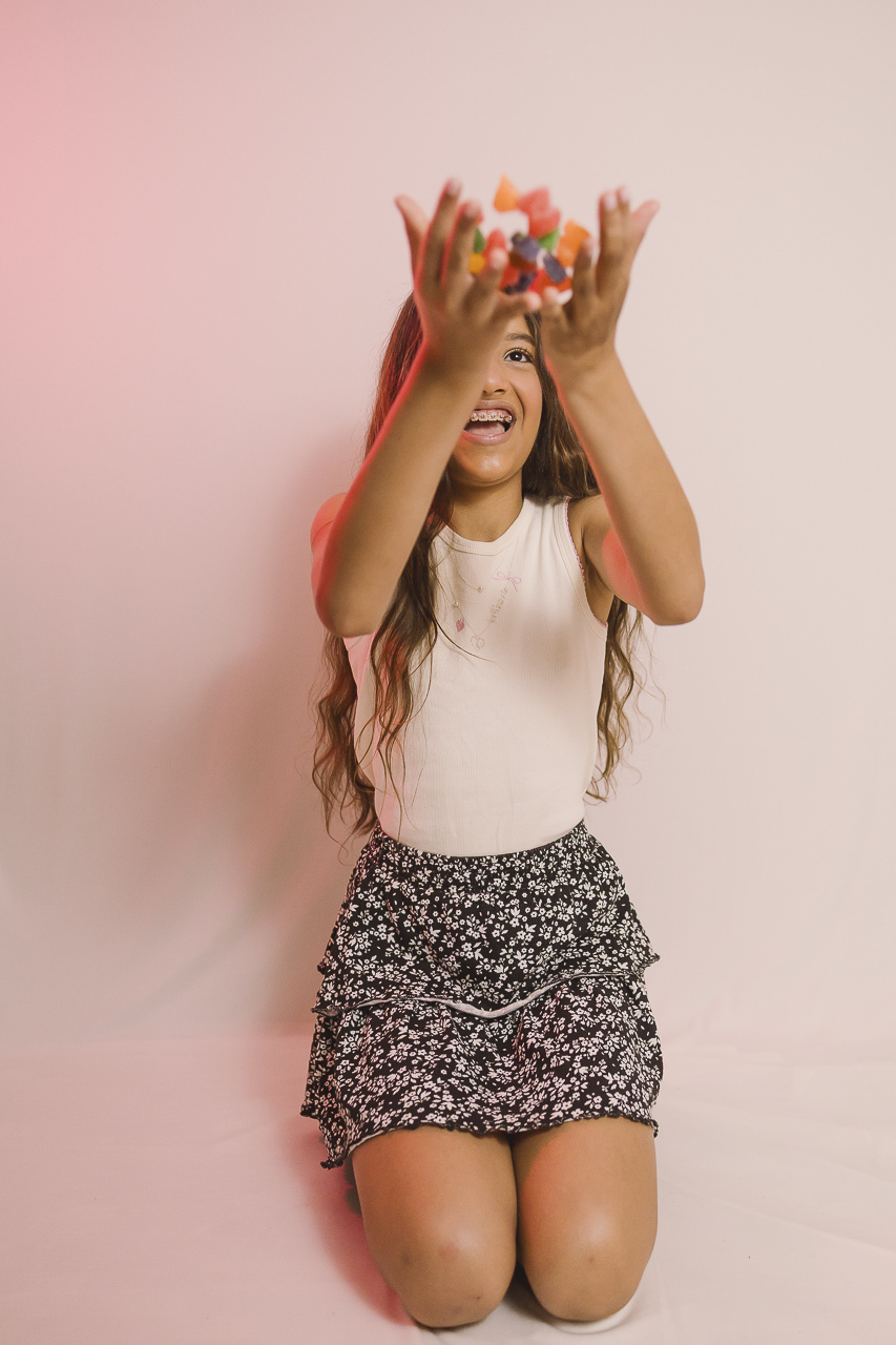 menina rindo com jujubas na mão ensaio de aniversário feminino - fotografa em sbc sp