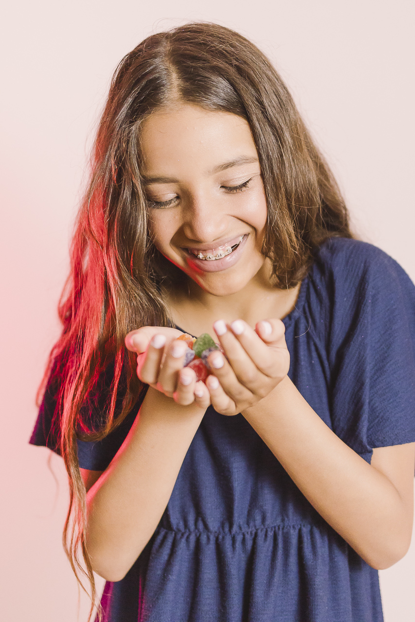 menina em ensaio de aniversário com balas de goma na mão - fotografa em sbc sp