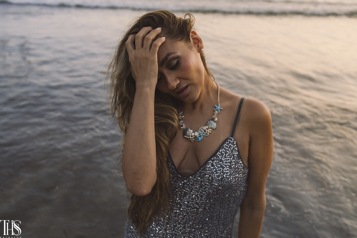 mulher sentada na beira da agua com vestido brilhoso ensaio na praia - fotografa em sp sbc