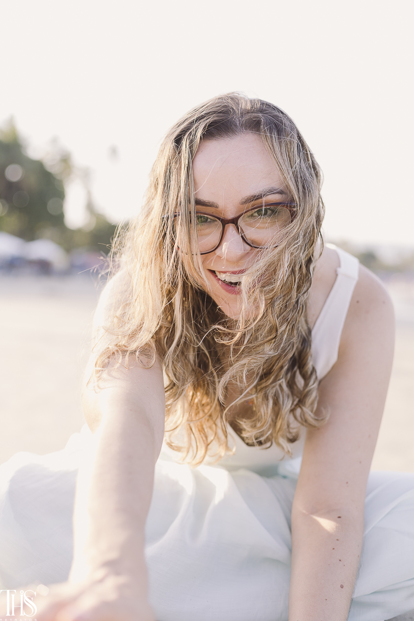 mulher de óculos sorrindo em ensaio feminino na praia - fotografa em sp sbc