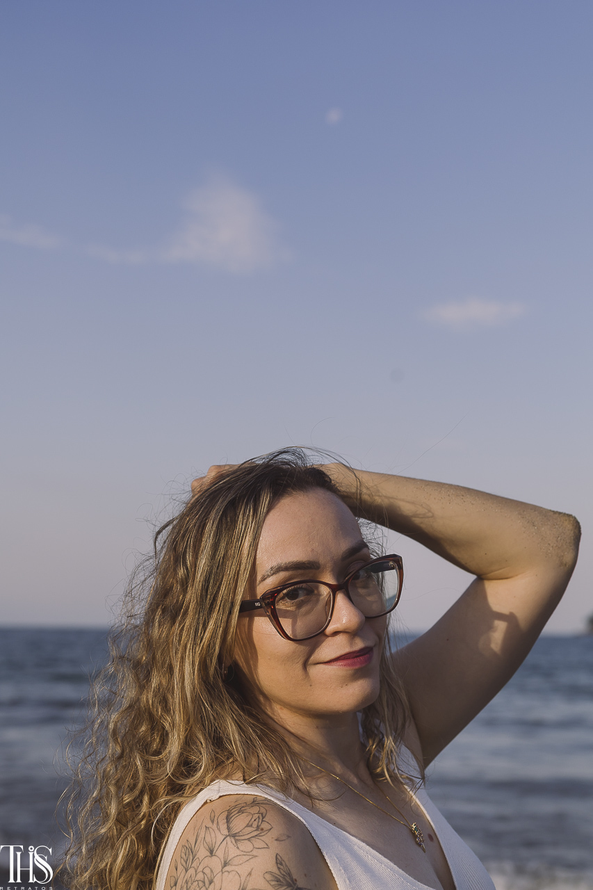mulher olhando para a câmera de óculos em ensaio na praia