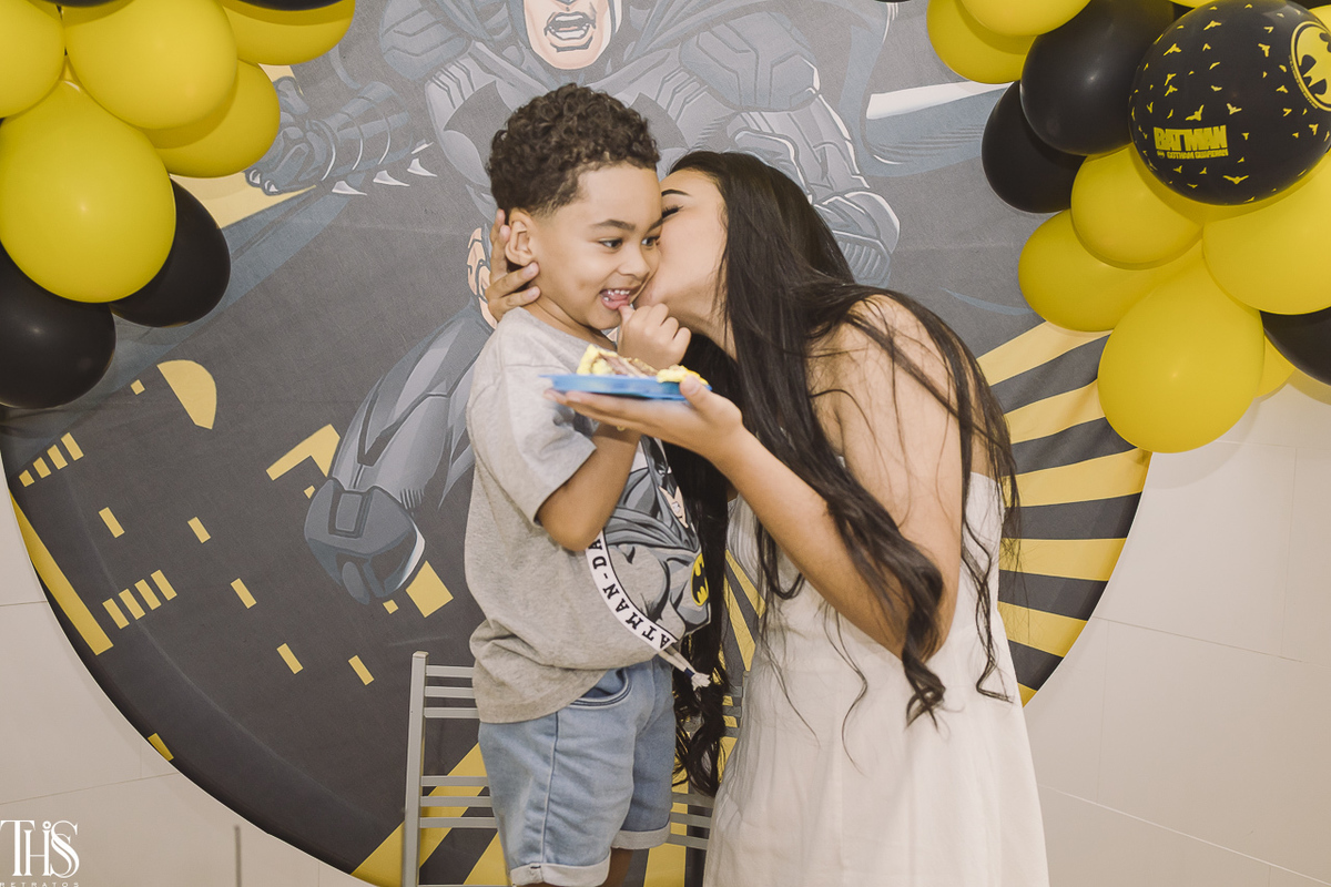 mãe beijando rosto do filho com primeiro pedaço do bolo em festa infantil - fotografa no abc