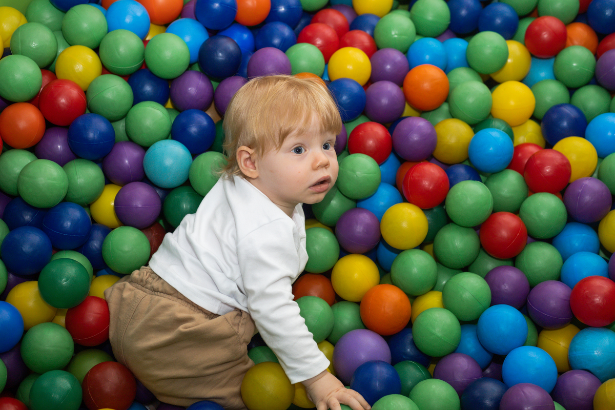 Foto do aniversariante atento dentro de uma piscina de bolinhas.coloridas 