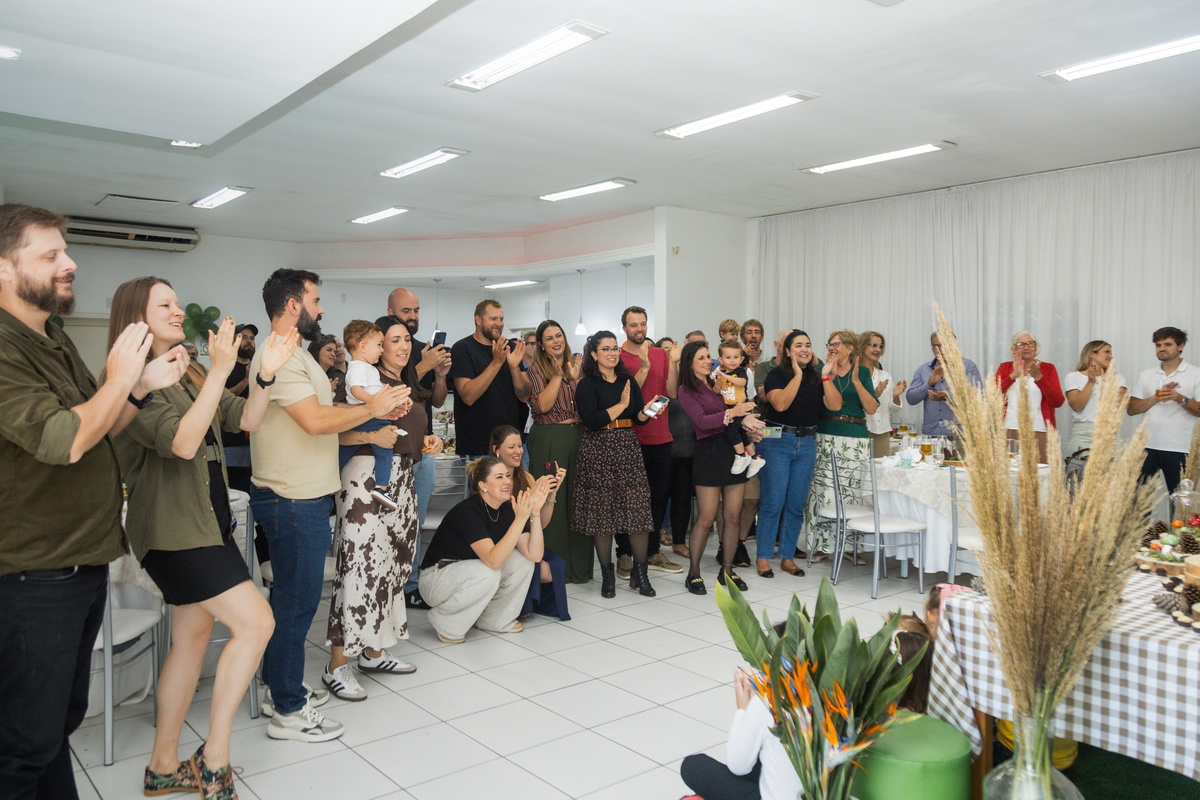 Foto em plano aberto, mostrando os convidados cantando o parabéns.