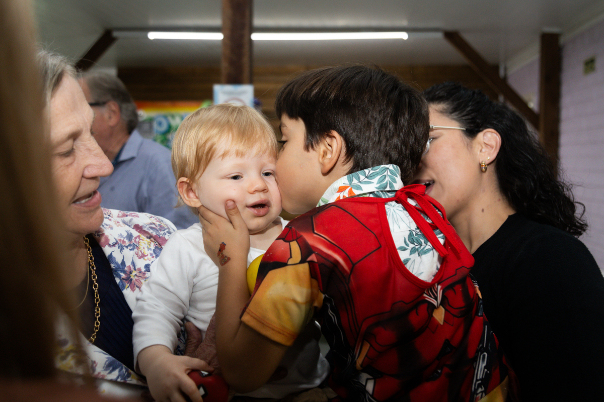 Foto do aniversariante recebendo um beijo no rosto, de um amiguinho.
