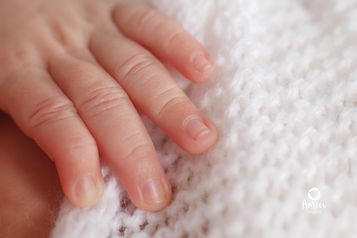 Fotografia macro, destacando os detalhes dos dedinhos da mão do recém nascido.
